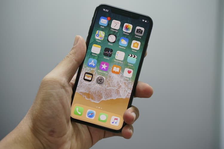 Hand holding a smartphone with a grid of app icons